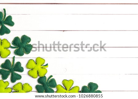 St.Patrick's day background with felt four-leaf clover on white wooden table. Space for text, top view. Lucky irish shamrock. 