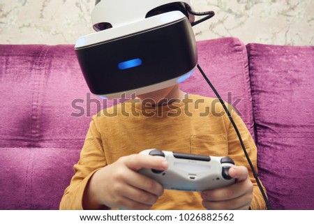 Caucasian boy is using virtual reality headset for playing video game at home.