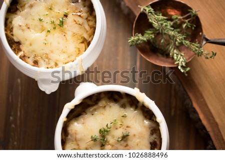 French Onion Soup with Thyme in classic white bowls with wooden background