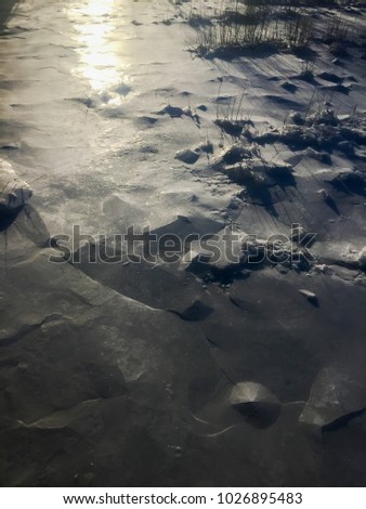 The sun shines at a low angle across ice on a river.