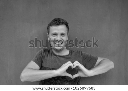 Black and white photo of caucasian man making a hand heart frame. Story of love from the past