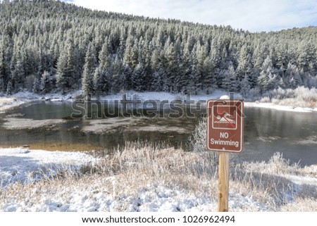 A no swimming sign in front of a small frozen pond in the Golden Gate Canyon State Park, Colorado.