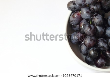Fresh red grapes and drop of water in a white bowl on white background. It's a fresh and healthy choice everyday