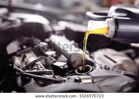 Motor oil pouring to car engine. Royalty-Free Stock Photo #1026970723