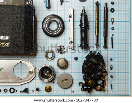 parts are completely disassembled old retro film SLR camera on graph paper, close-up