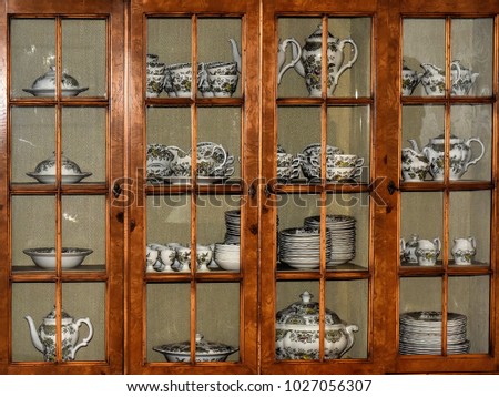 An old antique china cabinet filled with delicate china ware. Royalty-Free Stock Photo #1027056307