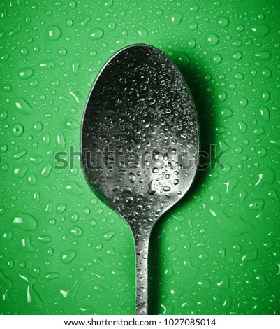 Spoons in droplets of water on a colored background.
