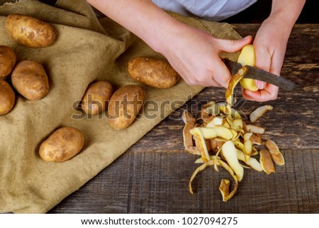 Detail of woman hands peeling fresh yellow potato with kitchen peeler, Food preparation concept.