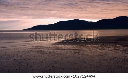 A lone fisherman at Sunrise on Trinity Bay in Cairns Queensland Australia with clouds morning clouds relefected in the water