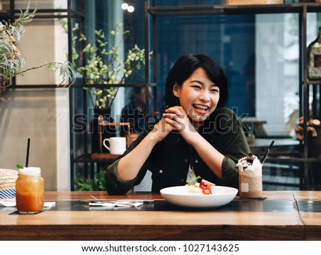 Happy young Asian woman food blogger joyful with food in restaurant.