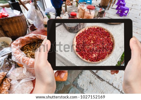 travel concept - tourist photographs dried spicy red pepper on local market in Chengyang village of Sanjiang Dong Autonomous County in spring in China on tablet