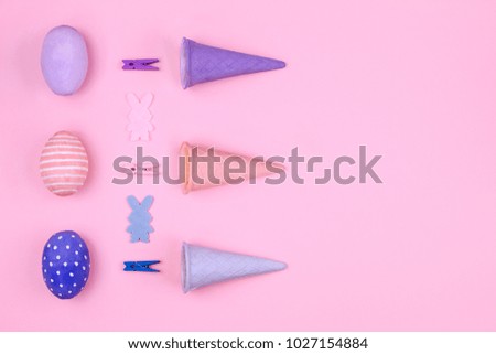 Happy Easter Day. Pink, blue and violet easter eggs, colorful clothespin, waffle cone and silhouette of rabbit on pink background
