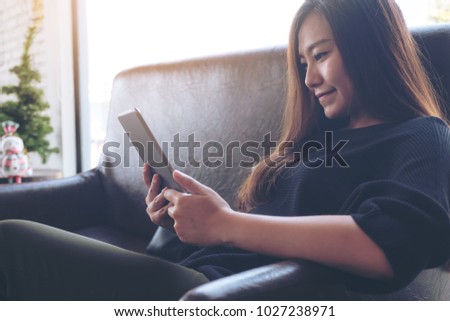 Closeup image of a beautiful asian woman holding and using tablet pc in cafe