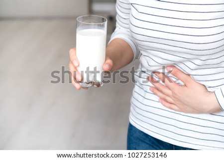 Lactose intolerance, health problem with dairy food products concept. Woman holding glass of milk having bad stomach ache. Royalty-Free Stock Photo #1027253146