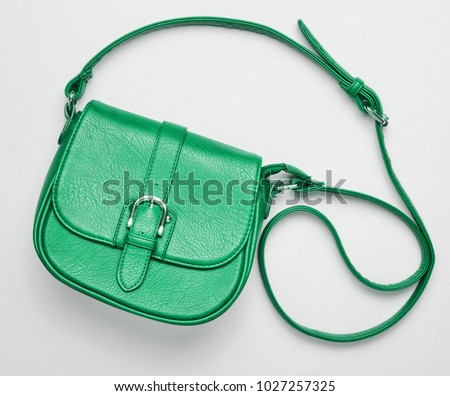Fashionable green leather bag on a white background. Top view, women's accessories. Royalty-Free Stock Photo #1027257325