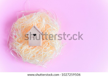 Wooden bird feeder and  in a straw nest on a pink background, Top view free copy space. Flat lay. Easter concept.