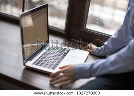 child is looking for cartoons on Internet. Learning on laptop. Hometown assignments online. child with laptop sits on window sill near window.