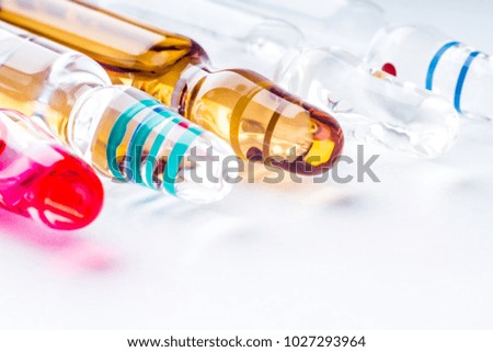 Colorful vitamin ampoules, and medicine capsules on an abstract white background. Healthcare, medical and pharmaceutical concept. Detailed close up studio shot with soft selective focus.