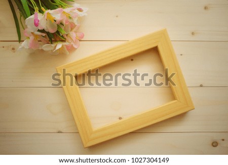 Wooden frame and flower on wooden background.