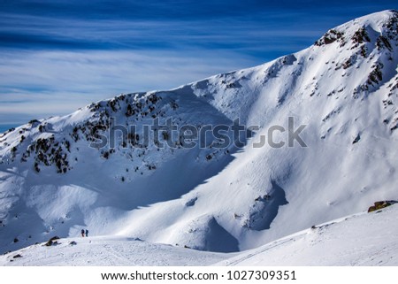 Two skiers, steep and snowy alpine mountain background, Dolomites, Italy