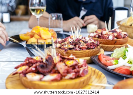 People eating Pulpo a la Gallega with potatoes. Galician octopus dishes. Famous dishes from Galicia, Spain. Royalty-Free Stock Photo #1027312414