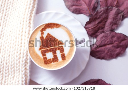 coffee cappuccino in a white cup with a picture of a house made from cinnamon on milk foam