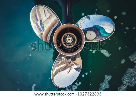 Close up image of  Three bladed stainless steel Boat Engine propeller in the water background. Royalty-Free Stock Photo #1027322893