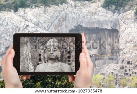 travel concept - tourist photographs The Big Vairocana statue on West Hill of Chinese Buddhist monument Longmen Grottoes (Longmen Caves) from the east bank of the Yi River in spring season on tablet
