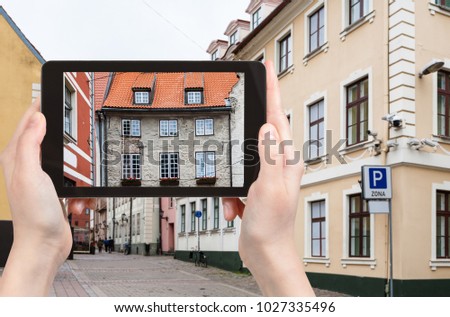 travel concept - tourist photographs house over Swedish Gate on Troksnu iela of Riga old town in Latvia in autumn on tablet