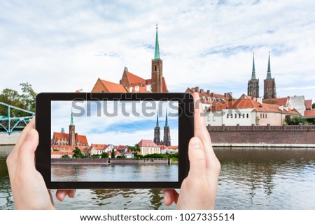 travel concept - tourist photographs Tumski island in Wroclaw city from Oder river on tablet