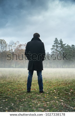 A man in a black coat in foggy weather