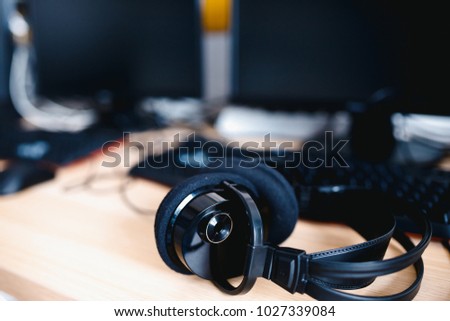 Close-up of headphones. In background computer, monitors for sound recording and games.