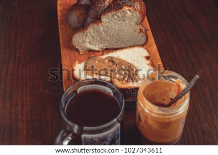 A delicious breakfast with coffee and peanut butter is smeared on a slice of bread