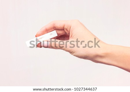 Female hand with pink fingernails holding negative white plastic pregnancy test isolated on pink background. Picture of a pregnancy test with not pregnant results.