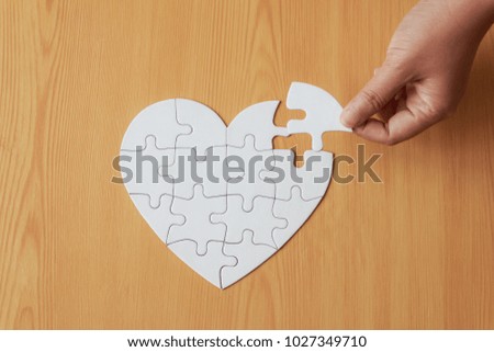 Close up shot hand of woman playing jigsaw puzzle on wooden table