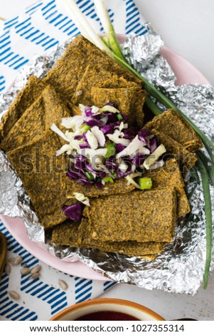 Crispy flax seeds bread dried with spices and herbs. With summer fresh salad of cabbage, red cabbage and onion. Raw, vegan, vegetarian healthy food concept.