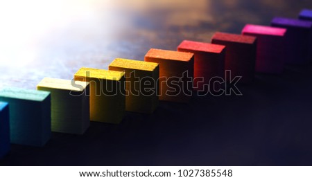Colored wooden blocks diagonally aligned on old vintage wooden table. For something with concept of variations or diversity. Plenty of copyspace. Shallow depth of field. Royalty-Free Stock Photo #1027385548