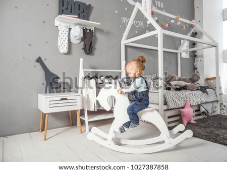 one year old girl playing near in the room with a toy horse, skating
