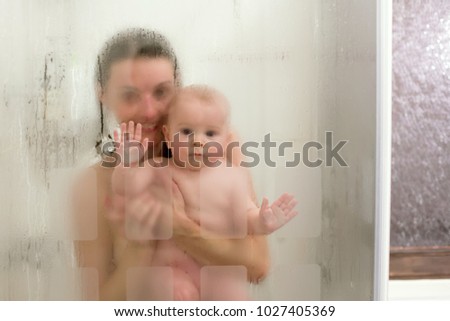 Mother and baby boy in shower, drops of water, picture through glass
