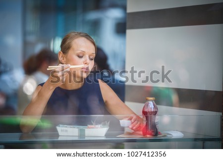 Pretty, young woman eating sushi in a restaurant, having her lunch break, enjoying the food, pausing for a while from her busy corporate/office life (color toned image)