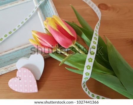 Tulips with vintage frame and white hearts laying on a wooden table