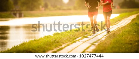 Couple running outdoors, at sunset, by a river, staying active and fit