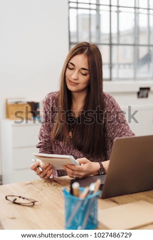 Young businesswoman sitting reading her notes with an engrossed expression in a bright office