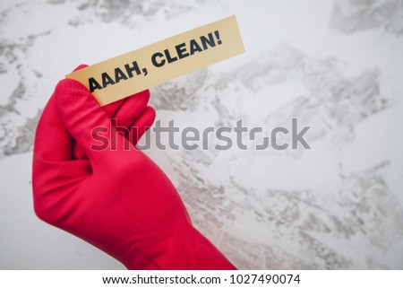 Cleaning office or house concept. Mens hand in red rubber glove holding AAAH, CLEAN inscription sign, concrete background, top view, copy space
