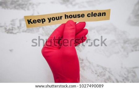 Cleaning office or house concept. Mens hand in red rubber glove holding Keep your house clean inscription sign, concrete background, top view, copy space