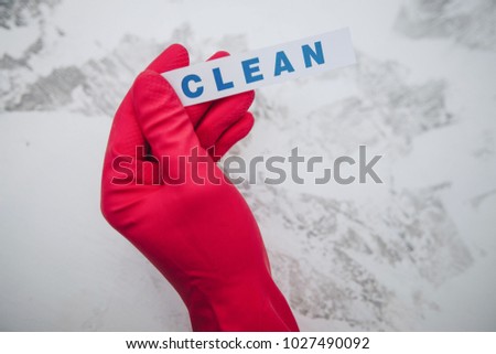 Cleaning office or house concept. Mens hand in red rubber glove holding CLEAN inscription sign, concrete background, top view, copy space