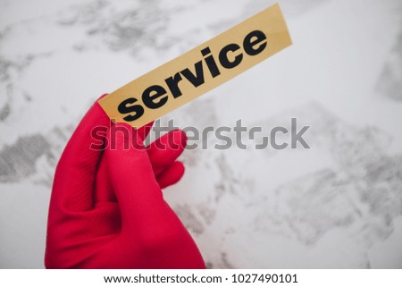 Cleaning office or house concept. Mens hand in red rubber glove holding Service inscription sign, concrete background, top view, copy space