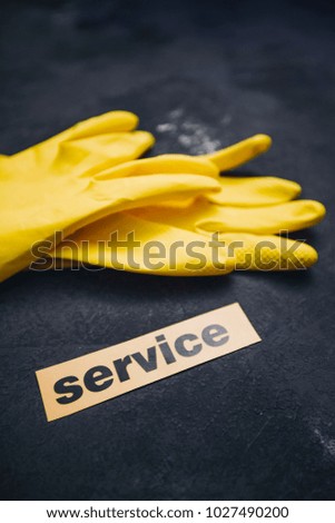 Cleaning office or house concept. Yellow rubber gloves and Service inscription sign, concrete dark background, top view, copy space