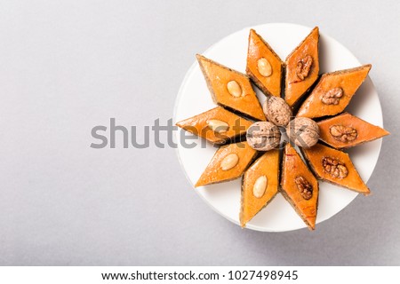 Traditional pakhlava baklava pastry from Azerbaijan made of walnuts and almonds with honey in round white plate cake stand on grey background, Novruz eastern new year spring celebration concept 