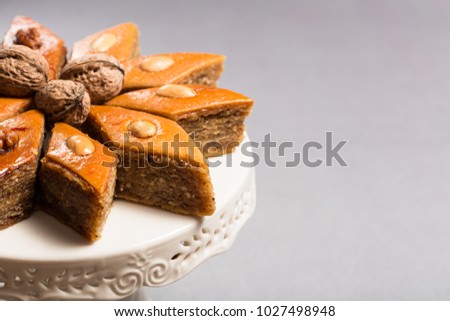 Traditional pakhlava baklava pastry from Azerbaijan made of walnuts and almonds with honey in round white plate cake stand on grey background, Novruz eastern new year spring celebration concept 